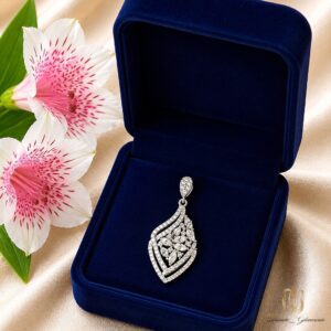 گردنبند نقره زنانه گل ne-new-43، نمایش گردنبند در جعبه مخمل آبی با گل لیلیوم سفید و صورتی کنار آن