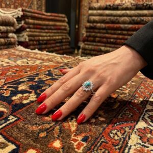 انگشتر نقره زنانه مجلسی نگین فیروزه ای | کد محصول ri-s-106، نمای دست با ناخن قرمز روی فرش شرقی