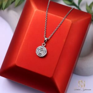گردنبند نقره زنانه پلاک دایره ای نگین باگت ظریف ne-new-81، عکس روی جعبه نمایش قرمز با برگهای سبز