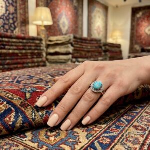 انگشتر نقره زنانه مجلسی نگین فیروزه ri-s-111 عکس دست زن با انگشتر روی فرش دستباف ایرانی